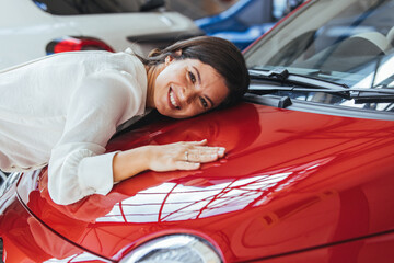 Joyful Woman Embraces New Red Car In Showroom Setting