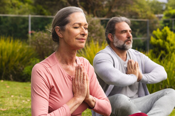 Fototapeta premium Mature couple meditating outdoors, finding peace and relaxation in nature