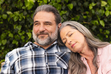 Relaxing outdoors, mature couple smiling as woman rests head on man's shoulder