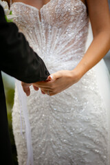Bride and Groom Holding Hands During Wedding Ceremony in Elegant White Bridal Gown