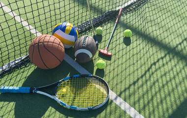A variety of sports equipment including an american football, a soccer ball, a tennis racket, a...