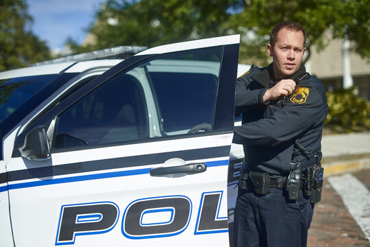 Man, talking and police officer at car with radio, communication and location update for safety in city. Cop, patrol and public service in Canada for security, law enforcement and surveillance report
