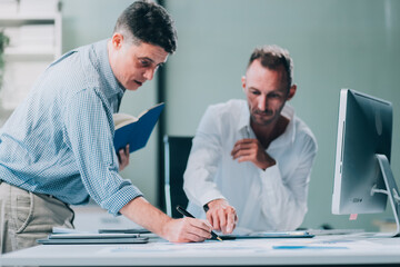 Two businessmen working together Analyze financial reports with charts and graphs while using the...