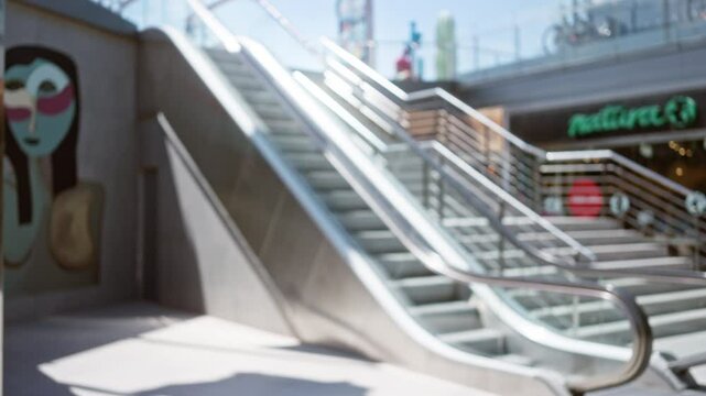 Blurred outdoor scene featuring stairs, metal railings, an urban background, defocused image art, seen in a sunny setting with a modern structure visible outdoors