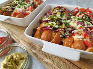 Baked Hot Dogs with Melted Cheese, Red Onions, and Pickles in Baking Dish