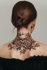 A detailed skull tattoo surrounded by flowers on the back of a woman, showcasing artistic body art in a minimalist studio setting