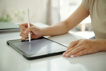 Person engaged with digital tablet, utilizing stylus for creative project in indoor environment....