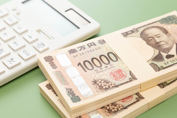 グリーン背景に一万円の札束と電卓