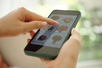 Close-up of hand selecting flower arrangement from smartphone screen in well-lit setting with...