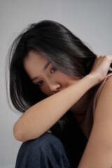 Fototapeta premium グレー背景で撮影をしたセーターを着た若い女性のスタイリッシュなポートレート