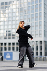 Young dancer performing urban dance in front of modern city buildings