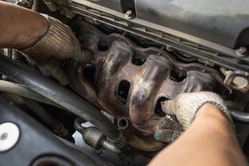 A car mechanic puts a manifold guard in place after replacing the gasket, close-up