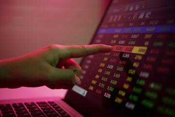 Hand interacting with digital display, exploring various stock market data highlighted in vibrant colors. Detail shows real-time numbers and graphs without focus on person