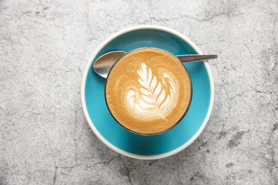 Top-down view of latte on blue saucer with teaspoon