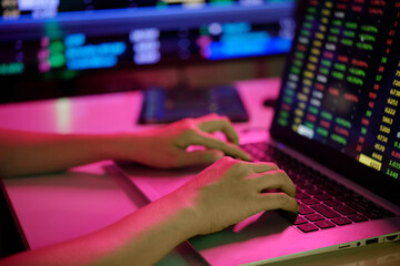 Close-up of hands typing on laptop with colorful stock market data. Reflecting focus and engagement during financial analysis in tech-driven environment