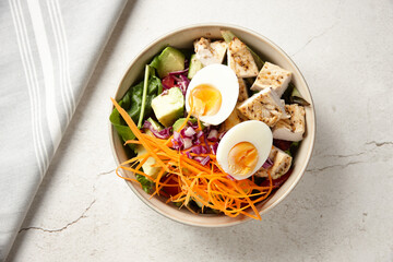 A bowl of chicken vegetable salad topped with boiled egg