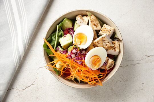 A bowl of chicken vegetable salad topped with boiled egg