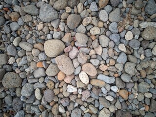 Background of smooth round pebble texture. Cover pebbles of various colors and patterns, gray pebbles, beige pebbles, reddish pebbles.  Gravel texture.