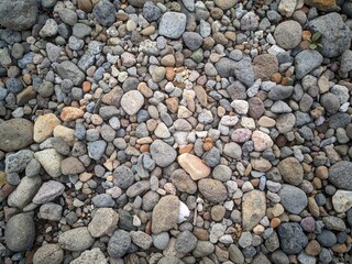 Background of smooth round pebble texture. Cover pebbles of various colors and patterns, gray pebbles, beige pebbles, reddish pebbles.  Gravel texture.