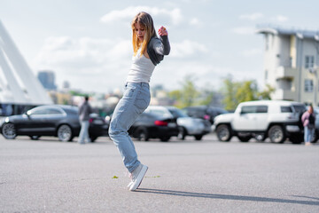 Young woman dancing joyfully in a parking lot during daytime © callisto