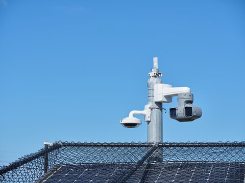 Solar panels with fences and a post with a light and camera
