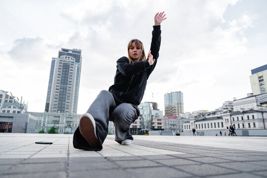 Young dancer performing a dynamic move in an urban setting during the day