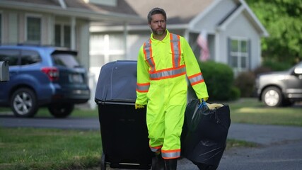 Garbage collector, dustman, trashman. A man pushes a large plastic trash bin for weekly waste disposal schedule. Man putting out rubbish in garbage bin at the street. Man throwing trash bag outdoors.