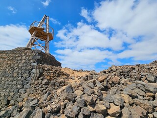 Un point de vue sur une structure en bois surélevée, installée au sommet d'un mur de pierre,...