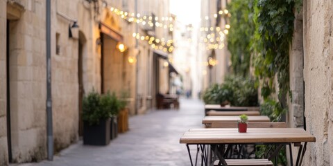 Fototapeta premium Charming street with empty tables and warm lights in a quaint alley.