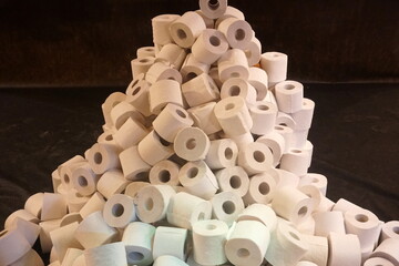 A pile of many white toilet paper on a black background. group of many rolls of toilet paper. A lot...