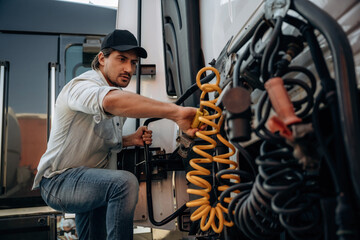 Messing with cables, installation, fix. Truck driver is near the transport outdoors