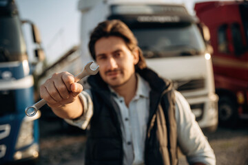 Tool in hand. Truck driver is near the transport outdoors