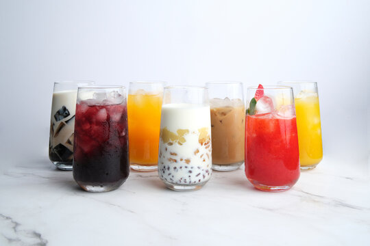 Different kinds of colorful juices in a tall glass served on a white marble countertop