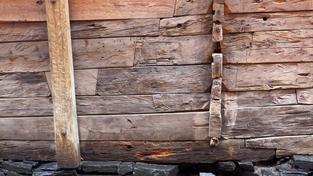 Tilt up shot of old wood timber log balk wall in heavy rain.