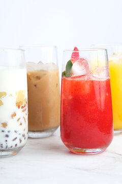 Different kinds of colorful juices in a tall glass served on a white quartz countertop