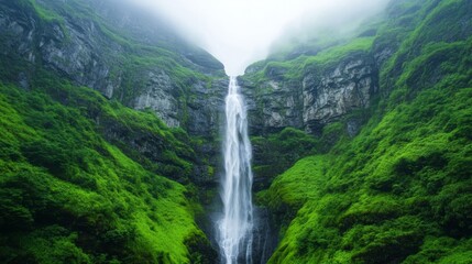 A waterfall cascading down the side of a towering mountain, surrounded by moss-covered rocks and mist for International Mountain Day 