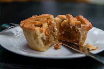 Close-up side view of mini apple pie with cinnamon and lattice shaped top cut in half lying on...