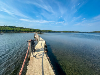Bicycle on bridge Scuza Trockenmauer connecting coastal towns Pomer and Premantura, Istria peninsula, Croatia, Europe. Touristic biking road along the coastline of Medulin, Kvarner Bay, Adiratic sea