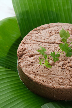 Vietnamese liver pate served in a banana leaf topped with an herb.