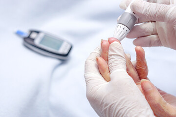 Doctor wear gloves using lancet on finger for checking blood sugar level by Glucose meter. Health...