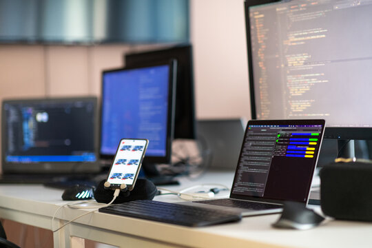 Computer screens running programming code in empty software developing agency office and computers parsing data algorithms in background. Neural network servers cloud computing in data room.