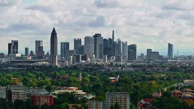 tele shot Drone video with zoom lens compressed of Frankfurt's skyline on a partly cloudy day. modern skyscrapers, historic buildings, and the dynamic cityscape under a bright, mixed sky  move left