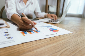 Businessman or accountant is analyzing data charts, graphs and dashboards on laptop screen to prepare statistical report.