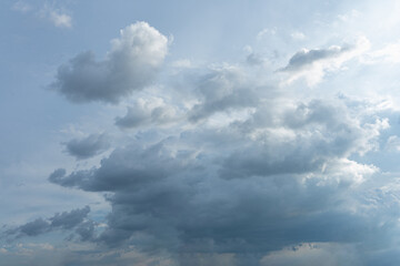 Fluffy white clouds drift across a bright blue summer sky