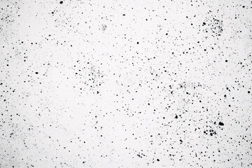 White textured surface with scattered black speckles resembling concrete or paint splatter creating an abstract minimalist pattern
