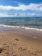 Issyk-Kul Lake with a cloudy sky and mountains in the background. The water is calm, reflecting the sky. The serenity and peacefulness of nature in the early morning hours.