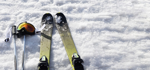 Mountain skis, sunscreen mask and ski sticks on bright alpine snow. Winter holidays. Extreme sport. Vacation, travel content. Banner with copy space