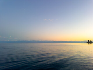 Issyk-Kul Lake with a cloudy sky and mountains in the background. The water is calm, reflecting the...