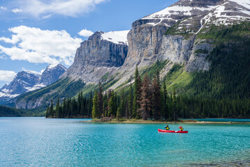 People canoeing on Maligne Lake near the spirit island. Snow-capped mountains and turquoise lakes scenery in Jasper National Park, Alberta, Canada. Canadian Rockies.