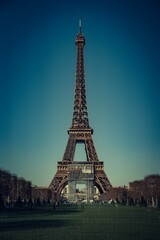 Eiffel Tower under a clear blue sky in Paris, France, surrounded by green lawns and trees
